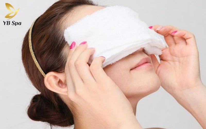 Chườm khăn ấm trong 10-15 phút giúp nhiệt độ tác động sâu, làm mềm các nút thắt bã nhờn cứng đầu một cách nhanh chóng